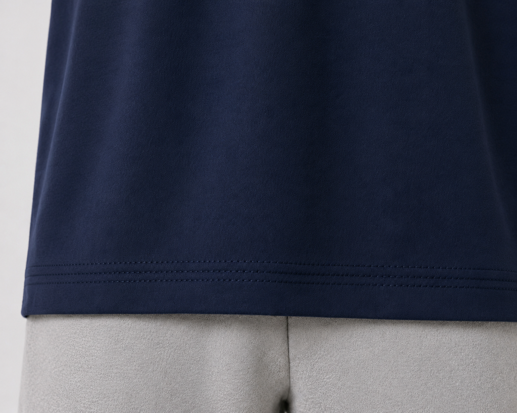 Close-up of a navy blue t-shirt hem with double-pointed stitching, shown on a light gray mannequin torso.
