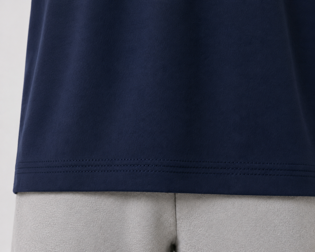 Close-up of a navy blue t-shirt hem with double-pointed stitching, shown on a light gray mannequin torso.