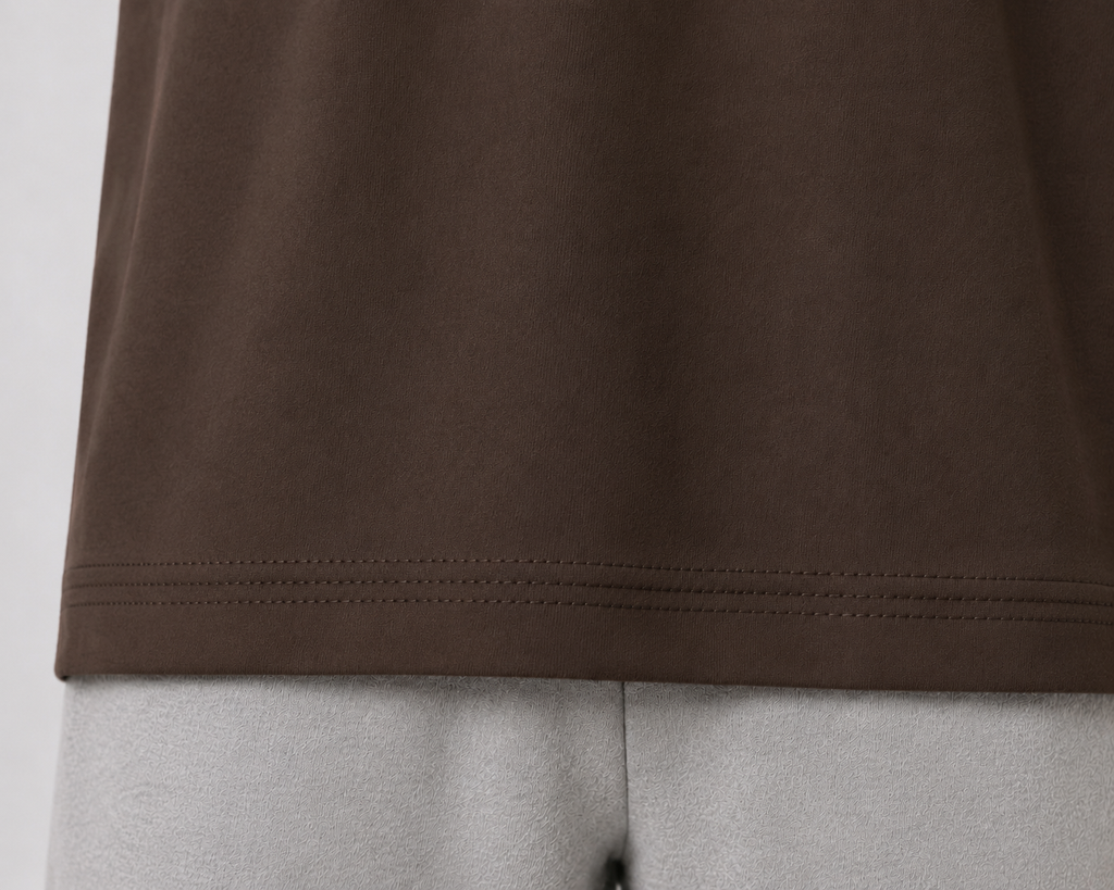 Close-up of a dark brown t-shirt hem with double stitching, shown on a light gray mannequin torso.