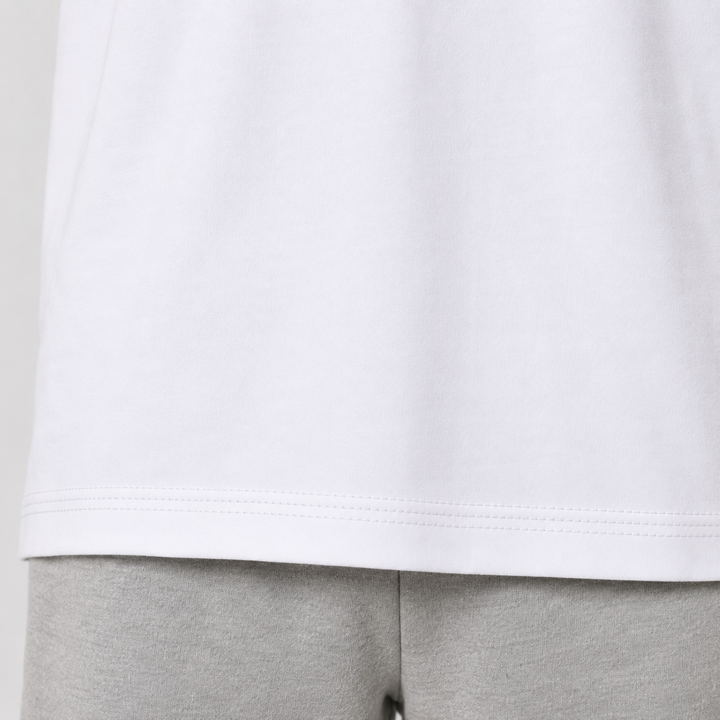 Close-up of a white short-sleeve top hem with gray sweatpants below, showing the stitched edge and fabric texture.