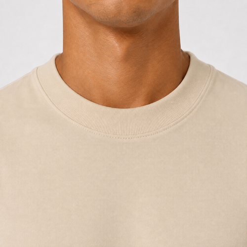 Close-up of a person's neck and lower face wearing a plain beige crewneck t-shirt against a light gray background.